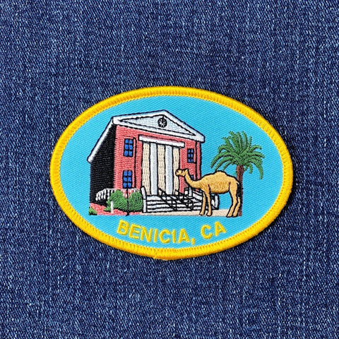 Embroidered patch of the historic Benicia Capitol building with a camel and palm tree on denim fabric