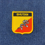 Embroidered patch with 'Bhutan' text and a dragon design on blue fabric.