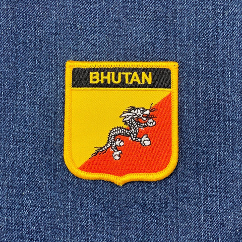 Embroidered patch with 'Bhutan' text and a dragon design on blue fabric.