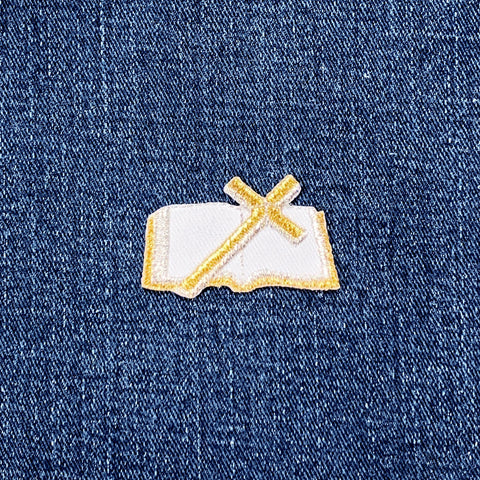 Embroidered patch of a bible and cross on denim fabric