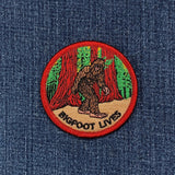 Embroidered patch with a Sasquatch design and 'Bigfoot Lives' text on denim fabric.