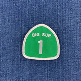 Green patch with 'BIG SUR 1' text made to resemble a California highway 1 road sign on a denim background