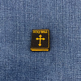 Embroidered patch of a 'Holy Bible' with a cross on blue denim fabric.