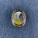 An oval metal medallion featuring the Black Canyon of the Gunnison National Park design, resting on a blue denim fabric background.