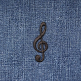 Black treble clef symbol patch on blue denim fabric