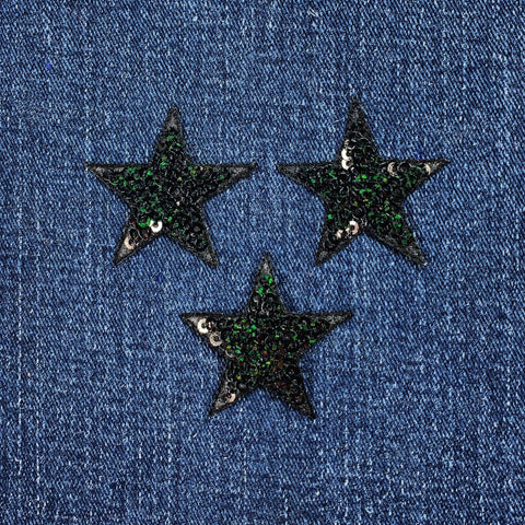 Three black star-shaped sequin patches on a denim background