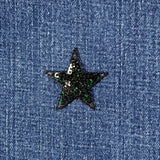 Black star-shaped sequin patch on blue denim fabric