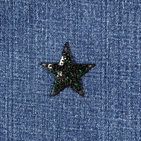 Black star-shaped sequin patch on blue denim fabric