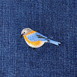 Embroidered bird patch on denim fabric