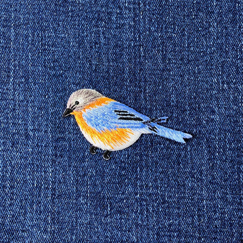 Embroidered bird patch on denim fabric