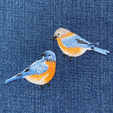 Two embroidered bluebirds on a denim background