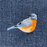 Embroidered bird patch on denim fabric