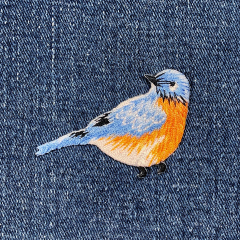 Embroidered bird patch on denim fabric