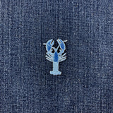 A blue embroidered lobster patch with raised stitched details, shown on a denim background.