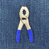 Patch of pliers with blue handles on denim fabric