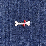 Bone-shaped patch with a pink bow on a denim background