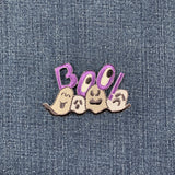 Embroidered patch with the word 'BOO!' in purple letters, accompanied by stylized ghosts in gray tones on a denim background