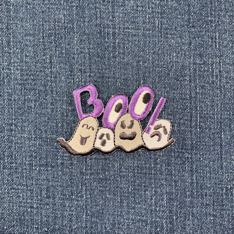 Embroidered patch with the word 'BOO!' in purple letters, accompanied by stylized ghosts in gray tones on a denim background