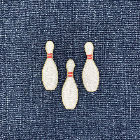 Three embroidered bowling pins on denim fabric