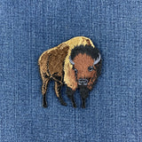 Embroidered buffalo applique patch with a brown, black, and beige design on a denim background.