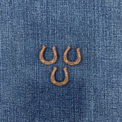 three brown horseshoe patches on a denim background
