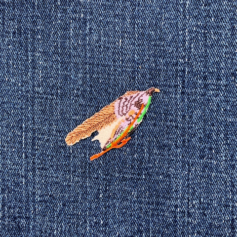 Small embroidered fly fishing lure patch on denim fabric