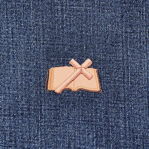 Patch of a brown and tan bible on blue denim fabric