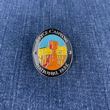 An oval enamel Walking Stick Medallion featuring a Bryce Canyon National Park design, displayed on a blue denim fabric background.
