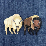 Two embroidered bison patches on a denim background
