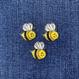 Three bee-shaped patches on a denim background