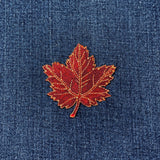burgundy maple leaf patch on blue denim fabric