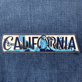 Decorative sticker with 'California' text and nature illustrations on a denim background