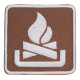 An embroidered square patch featuring a white campfire symbol on a brown textured background with a white border.