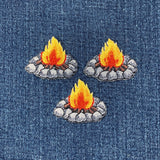 Three embroidered campfire patches on denim fabric