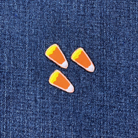 Three candy corn-shaped patches on a denim background