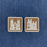 two embroidered patches on a denim background: a castle patch and a cathedral patch resembling European road signs