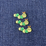 Three green caterpillar-shaped patches on a denim background