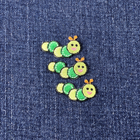 Three green caterpillar-shaped patches on a denim background