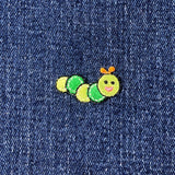Embroidered green caterpillar patch on denim fabric