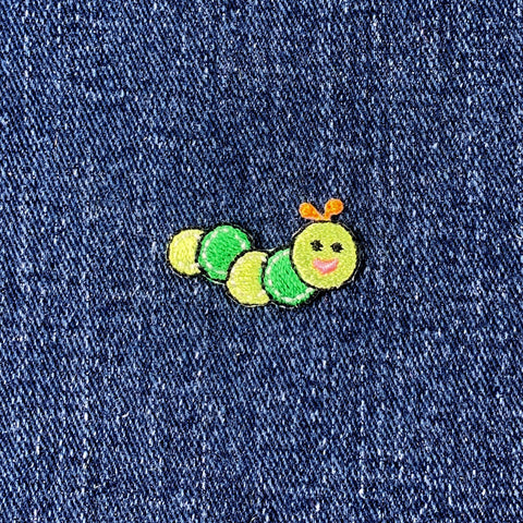 Embroidered green caterpillar patch on denim fabric
