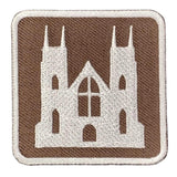 An embroidered square patch featuring a white silhouette of a Gothic cathedral on a brown background with a white stitched border.