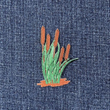 embroidered reeds and cattails patch on a denim background