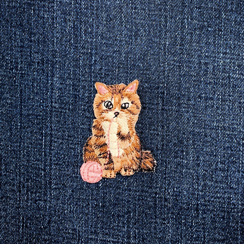 cat with pink yarn patch on a blue denim background