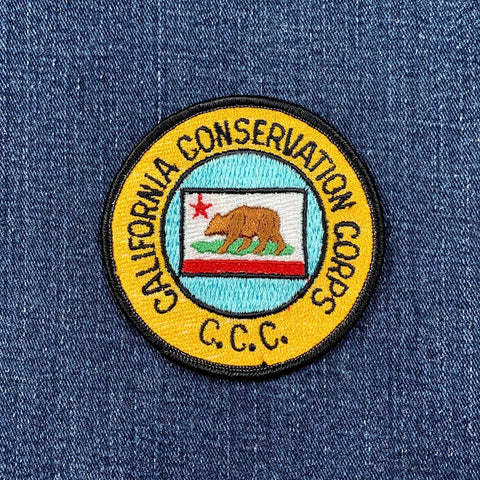 A round vintage patch featuring the California Conservation Corps emblem on a denim background