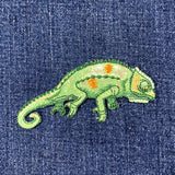 Embroidered chameleon patch on a denim fabric background