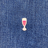 Embroidered patch of a glass with sparkling wine on blue denim fabric