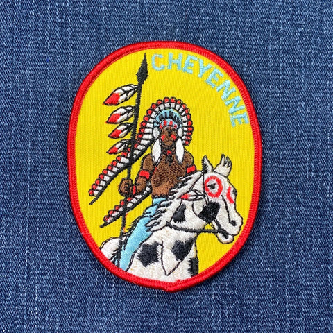A vintage Cheyenne patch featuring an embroidered Indian figure on horseback with a headdress, against a yellow background with the text 'CHEYENNE' across the top on a denim background.
