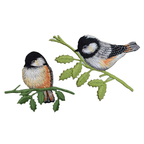Two embroidered bird designs on a branch with leaves against a white background