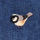 Embroidered bird patch on denim fabric
