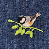 Embroidered bird patch on denim fabric